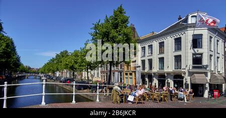 city of Leiden, provincof South Holland, Netherlands, Europe, people relax along the Dutch canal Rapenburg in the historic centeof Leiden., The citof Leiden is known for its secular architecture, his canals, his universitof 1590, the nativitof Rembrand, the city where flowered the first bulof tulip in Europe in the 16th century Stock Photo