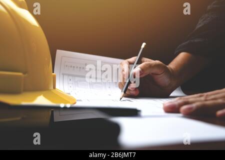 Architect's desk: Engineer works with drawings in a office. Instruments and office for designer. Close-up male hands draw with a pencil. Stock Photo