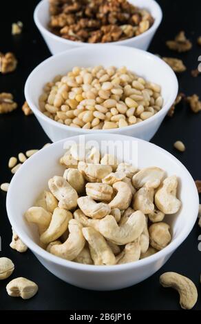 superfood concept, cedar, walnuts, cashew nuts in a plate on a black background Stock Photo