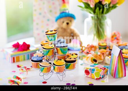 Cupcakes for kids birthday celebration. Jungle animals theme children party. Decorated room for boy or girl kid birthday. Table setting with presents, Stock Photo