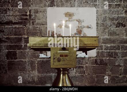 A candle holder in a church with lighted candles and offering box in Italy Stock Photo