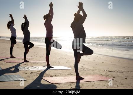 Side view of women doing yoga together at the beach Stock Photo