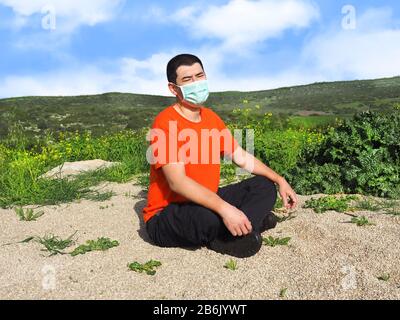 Worried Asian man in mask sitting on the ground. Asian man sitting in heavy thoughts about the virus. Stock Photo