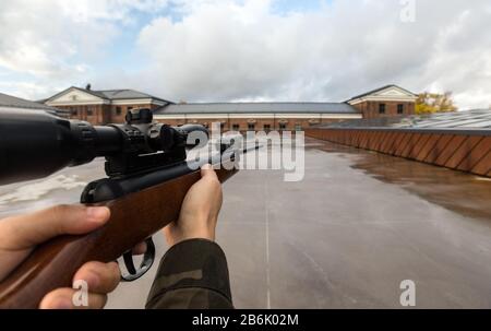 virtual reality game and violence concept - POV of male hands shooting with air rifle outdoors Stock Photo