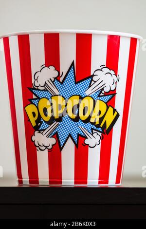 Plastic container for popcorn isolated close up photo. Popcorn sign on plastic and empty red and white striped bucket. Movie time concept. Stock Photo