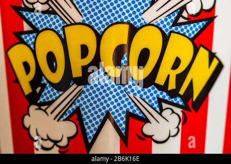 Plastic container for popcorn isolated close up photo. Popcorn sign on plastic and empty red and white striped bucket. Movie time concept. Stock Photo