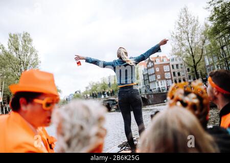 Orange party-goers take over the streets and canals of Amsterdam to celebrate the King's Birthday on Koningsdag. Stock Photo