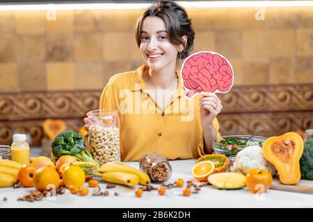 Woman holding human brain model with variety of healthy fresh food on the table. Concept of balanced nutrition for brain health Stock Photo