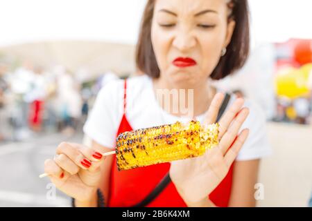 A woman refuses to eat sweet corn. The concept of spoiled food and junk food Stock Photo