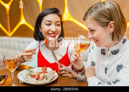 Two female friends Drink wine and enjoy meal at the restaurant Stock Photo