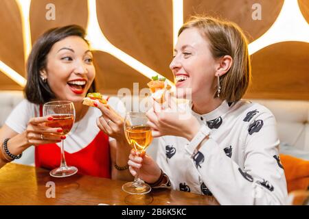 Two female friends Drink wine and enjoy meal at the restaurant Stock Photo