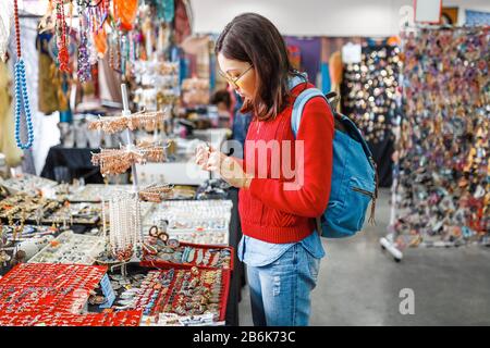 Trendy hipster asian woman looking for fancy jewelry and accessories in a flea market shop Stock Photo