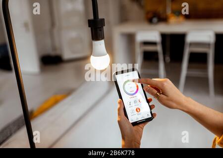 Controlling light bulb temperature and intensity with a smartphone application. Concept of a smart home and managing light with mobile devices Stock Photo