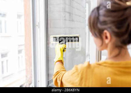 Woman washing windows with a special cleansing device at home. Concept of a professional housekeeping Stock Photo