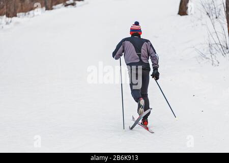 Man wearing sports uniform on cross-country skiing in a city park, healthy lifestyle concept Stock Photo