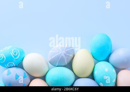 Colorful Easter eggs dyed by colored water with beautiful pattern on a pale blue background, design concept of holiday activity, top view, copy space. Stock Photo
