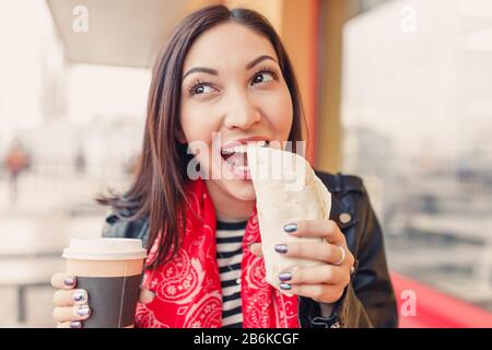 portrait of pretty woman drinking a cup of coffee and eating snack in a fast food cafe Stock Photo