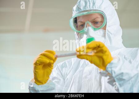 Female epidemiologist using medical sample test tube in virus quarantine