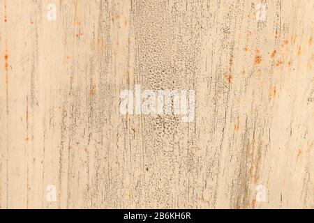 Old rusty metal wall covered with beige cracked peeling paint with spots of rust. Abstract modern trendy texture background Stock Photo