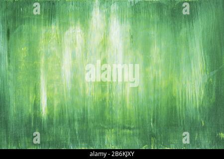 Traces of brush strokes of yellow and green paint on the surface of a wooden wall with spots, scuffs and scratches. Abstract trendy green paint textur Stock Photo