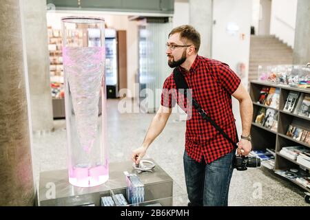 A hipster man wearing spectacles with a beard making an entertaining physical experiment with turbulent phenomena in the water Stock Photo