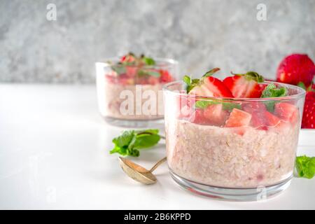 Set various fruit overnight oatmeal. Oats porridge with strawberry, bananas, chocolate, nuts in small portion jars. Summer breakfast oatmeal. Healthy Stock Photo