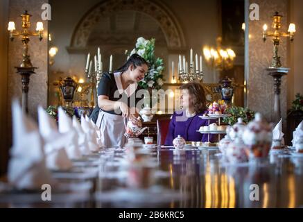 Emma Manner, Duchess of Rutland (right), is served tea by Lliana Dimitrove, during the launch event for a Royal Afternoon Tea inspired by Netflix's The Crown, in the state dining room at Belvoir Castle, Grantham. Stock Photo