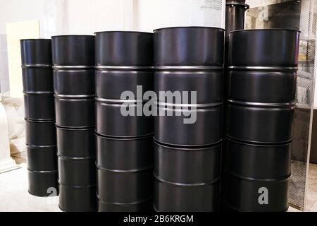 Row of black barrels indoors at the factory, concept of fuel raw materials for industry Stock Photo