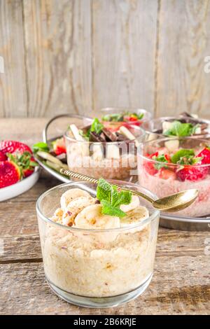 Set various fruit overnight oatmeal. Oats porridge with strawberry, bananas, chocolate, nuts in small portion jars. Summer breakfast oatmeal. Healthy Stock Photo