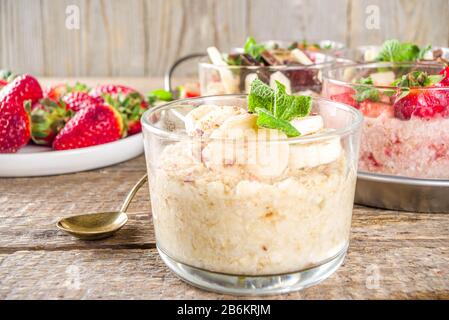 Set various fruit overnight oatmeal. Oats porridge with strawberry, bananas, chocolate, nuts in small portion jars. Summer breakfast oatmeal. Healthy Stock Photo