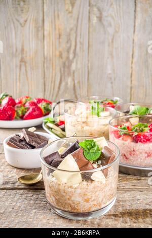 Set various fruit overnight oatmeal. Oats porridge with strawberry, bananas, chocolate, nuts in small portion jars. Summer breakfast oatmeal. Healthy Stock Photo