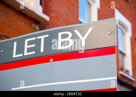 LET BY sign displayed on London street with traditional English terraced houses in the background Stock Photo
