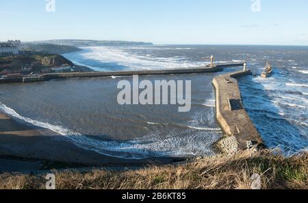 View of Whitby piers in Winter with a rough sea taken from the East Cliff Stock Photo