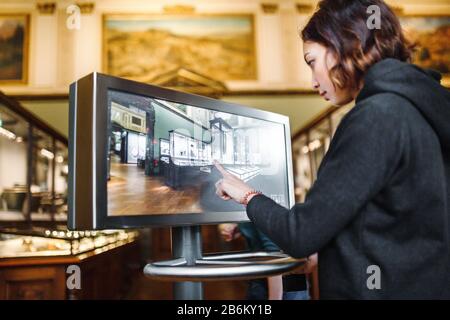 A woman in the museum uses the touchscreen monitor electronic guide, the concept of modern education Stock Photo