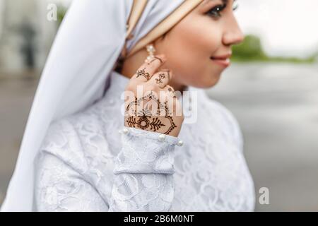 Charming muslim arabic bride in nikah wedding dress and hijab headscarf, close-up on jewelry and earrings Stock Photo