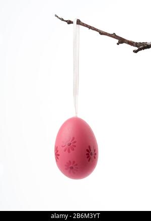 decorative plastic pink easter egg hanging on a branch, decor on a white background Stock Photo