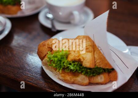 Croissant sandwiches and latte coffee served on cafe table. Breakfast with fresh bakery food and hot drink Stock Photo