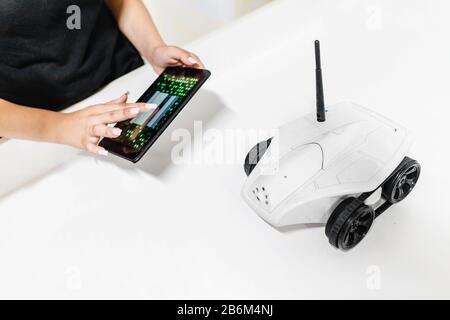 Car or rover robot on four wheels getting ready for work by female hand with smartphone Stock Photo