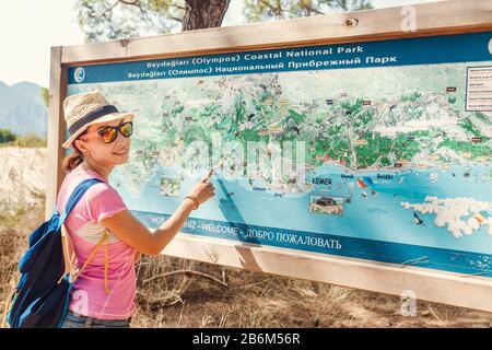16 SEPTEMBER 2017, CIRALI, TURKEY: A young woman exploring the map of the national coastal park Olympos in Turkey, the concept of travel and hiking Stock Photo