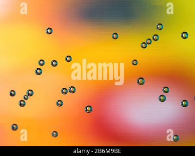 macro of air bubbles on water glass with yellow red and orange background Stock Photo