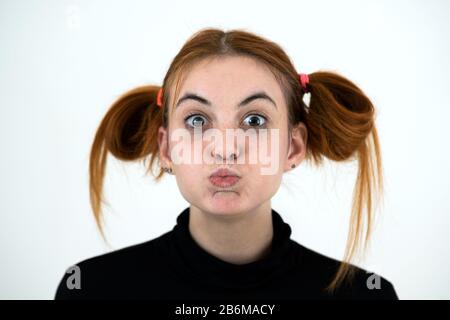 Closeup portrait of a funny redhead teenage girl with childish hairstyle isolated on white backround. Stock Photo