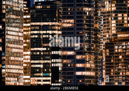 Facade windows of illuminated modern skyscraper with office building at night Stock Photo