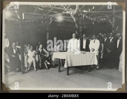 Feestelijke bijeenkomst met Nederlanders en Surinamers Festive meeting with Dutch and Surinamese. Three men standing at a table, left in the first row Edith Jetten in a chair. Photo with corners attached to a page of an album leaf in the photo album on the family Jetten and li and working in the mining town of Moengo in Suriname around 1927. Manufacturer : Photographer: anonymous place manufacture: Suriname Date: 1925 - 1927 Material: paper Technique: Photography Dimensions: h 125 mm × W 174 mm Subject: anonymous historical persons Portrayed in a group, in a group-portrait when: 1925 - 1927 Stock Photo