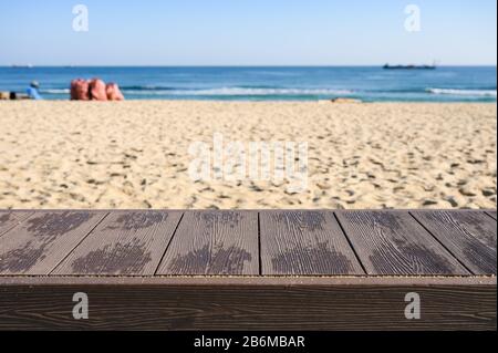 Empty wood tabletop on the beach with blue sky and garbage bags Stock Photo