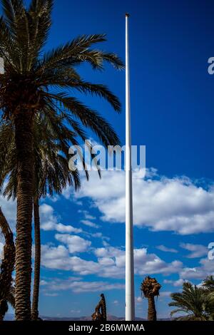 Jordan, Aqaba, Arab Revolt Flagpole as seen from the entrance of Aqaba Castle with palms and beautiful white clouds in the background. Sunny winter day Stock Photo