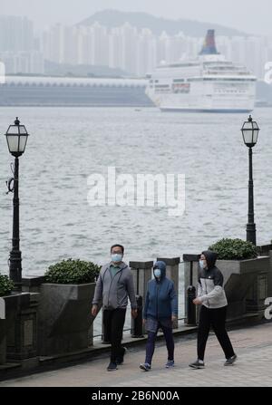 Hong Kong, China. 11th Mar, 2020. Citizens take a walk by the sea in Hung Hom of Hong Kong, south China, March 11, 2020. The total number of confirmed COVID-19 cases in Hong Kong has risen to 126, Hong Kong's Centre for Health Protection (CHP) said Wednesday afternoon. Credit: Wang Shen/Xinhua/Alamy Live News Stock Photo