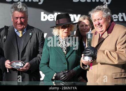 Trainer Paul Nicholls (left) and owner John Hales (right) with Camila, Duchess of Cornwall after winning the Betway Queen Mother Champion Chase during day two of the Cheltenham Festival at Cheltenham Racecourse. Stock Photo