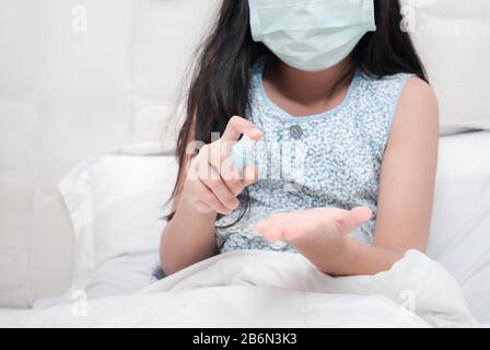 Asian girl wear hygienic mask and press alcohol spray to protect Wuhan coronavirus and epidemic virus. Coronavirus or covid-19 concept Stock Photo