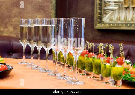 Glasses for champagne, filled and empty, stand on the table and wait for their owners. Stock Photo