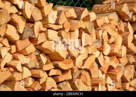 Closeup of a heap of firewood lying piled up in a garden in front of a fence. Seen in Germany in March. Stock Photo
